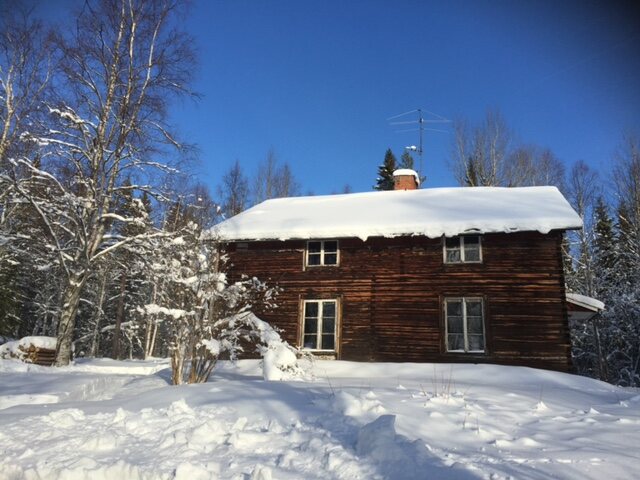 Dunkles Holzhaus im Schnee in Schweden
